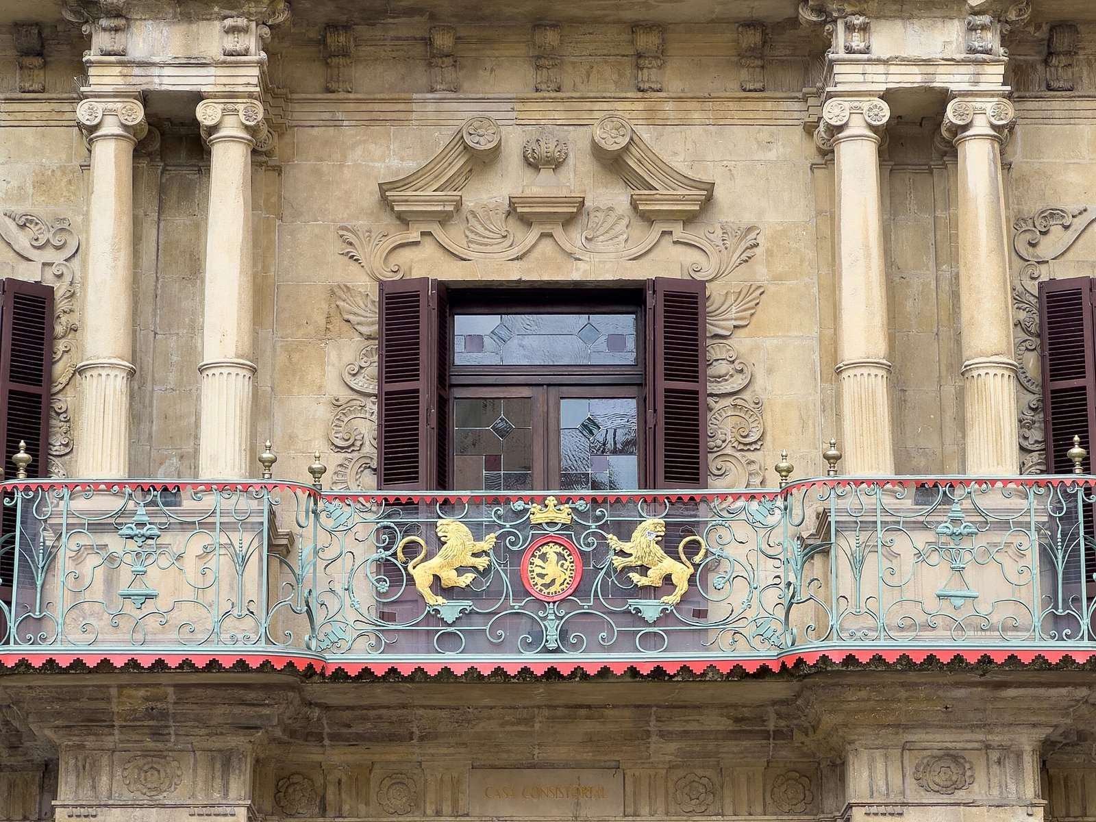 Balcón de forja con leones dorados y escudo en la fachada barroca de la Casa Consistorial de Pamplona-Iruña.